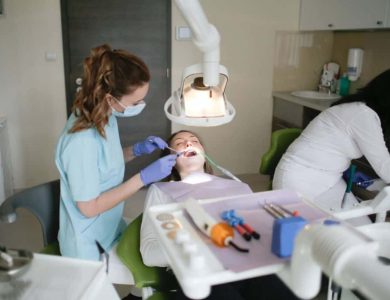 A Woman in Blue Dress Checking A Patient Teeth